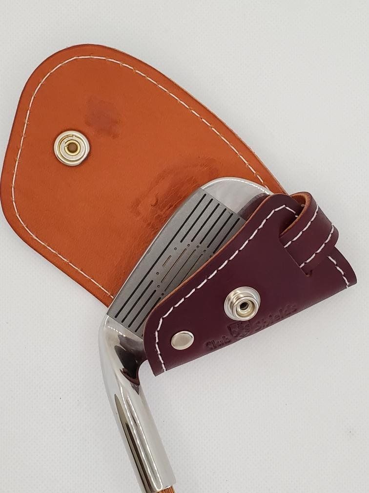 Golf club iron in a clubshield leather head cover.