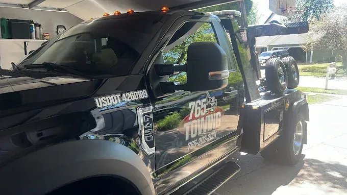 Black tow truck parked outside, displaying the company name 