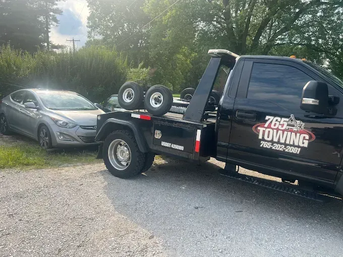 Gray car being towed by a black tow truck with 