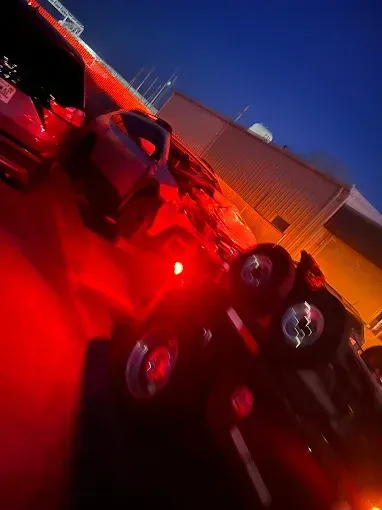 Red lights illuminate a semi-truck at dusk, parked outside a building.