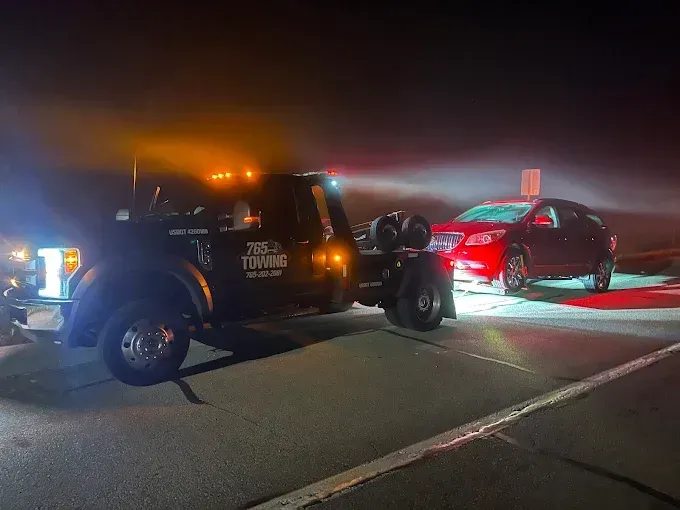 Tow truck loading a red car at night.