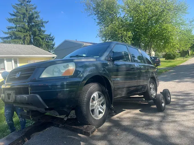 Dark SUV on a tow truck, parked on a residential street on a sunny day.