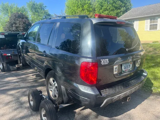 Dark gray SUV being towed on a sunny day.