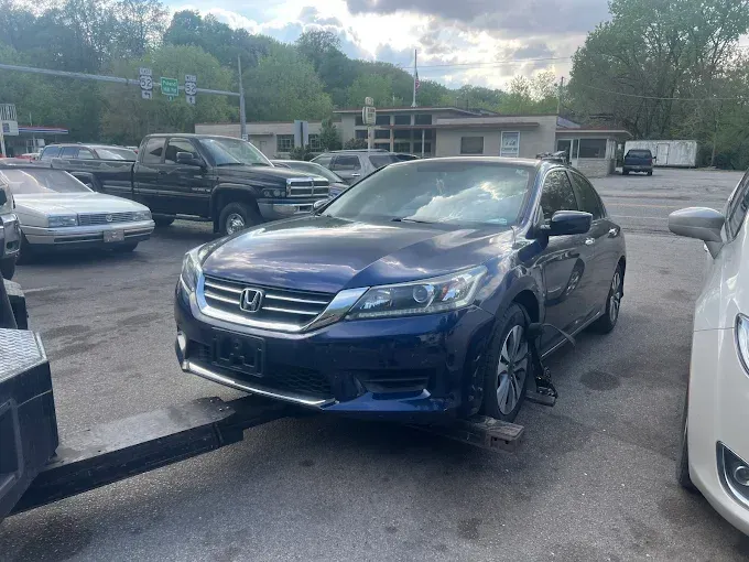 Blue Honda Accord on a tow truck, parked in a lot.