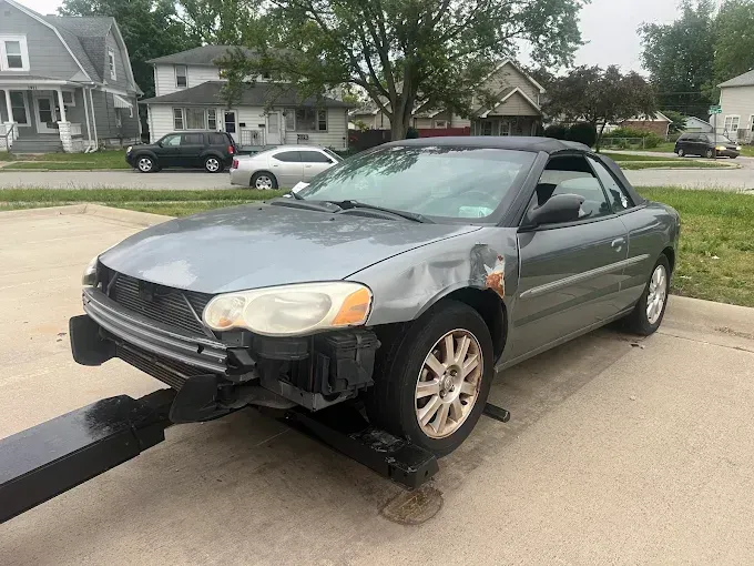 Damaged gray Chrysler Sebring convertible on a tow truck.