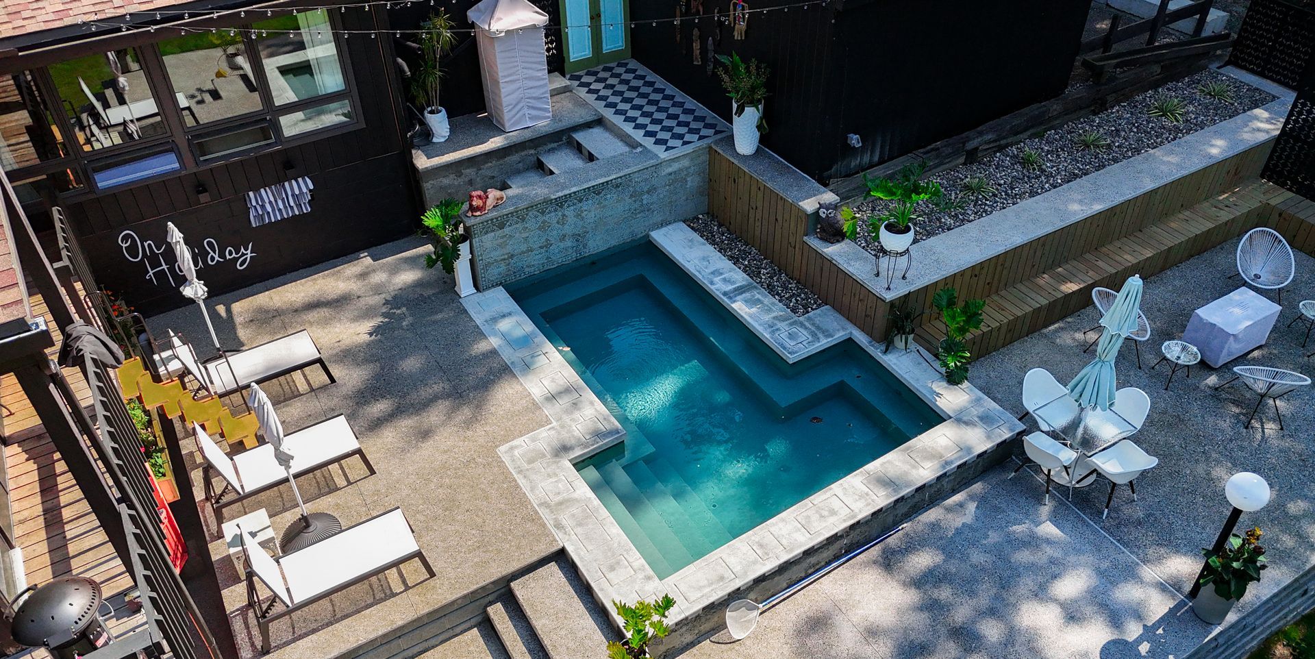 Aerial view of a backyard with a pool, lounge chairs, and seating areas.