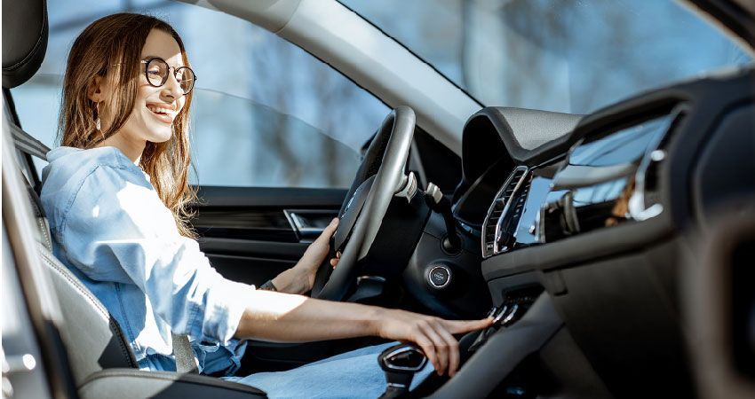 Woman in car, smiling, adjusting controls. Interior with dashboard, steering wheel.