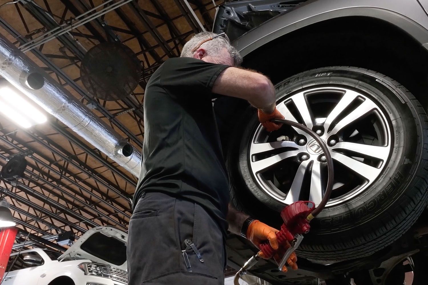 Mechanic using a wrench to work on a car wheel in an auto shop