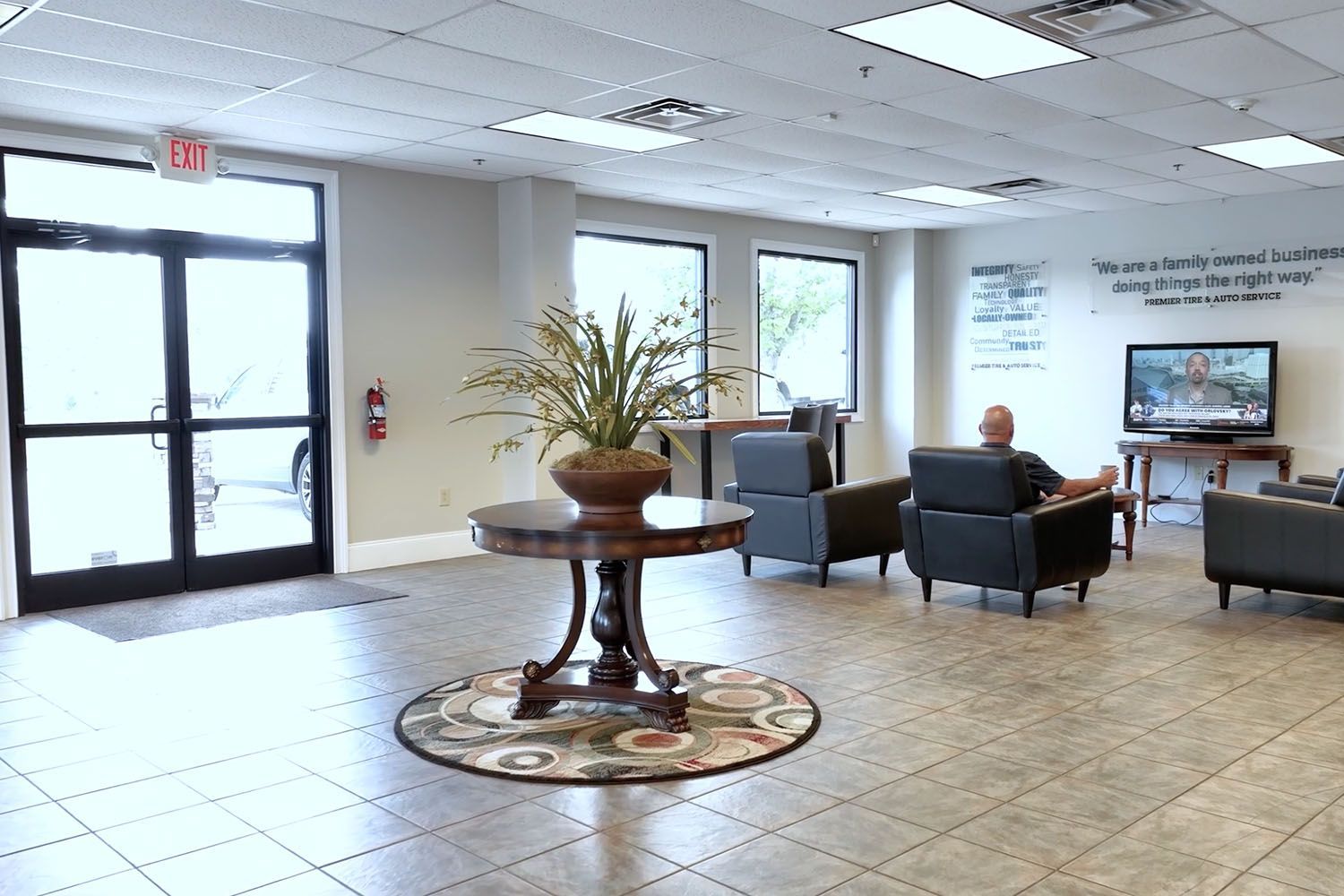 Lobby waiting area with chairs, glass doors, tiled floor, and a decorative table centerpiece