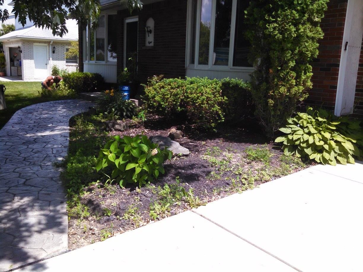 Front yard garden with curved stone walkway, shrubs, and a house porch
