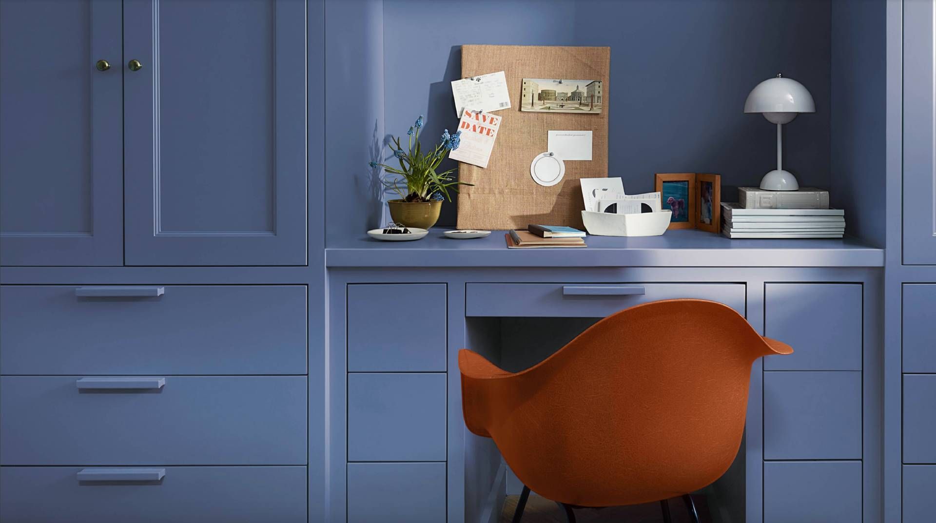 Bright orange chair sat in front of a desk and wall painted Blue Nova