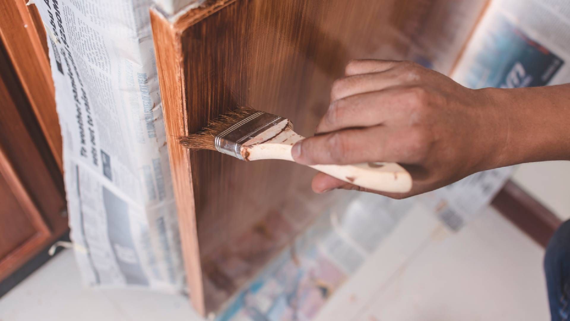 Person applying paint to a cabinet with a brush
