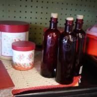 Several dark glass bottles and red-lidded containers on a shelf against a green pegboard.