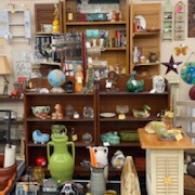 Antique shop shelves filled with colorful ceramics, glassware, and decorative items