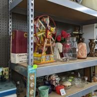 Shelves of assorted thrift-store decor, including a small Ferris wheel and glass vases