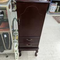 Dark wooden cabinet with drawers and curved legs in a store aisle