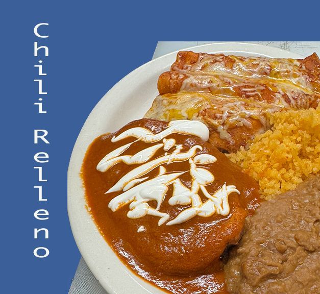 Two street tacos topped with cilantro and onions on a white plate with a fork, knife, and a wedge of lime.