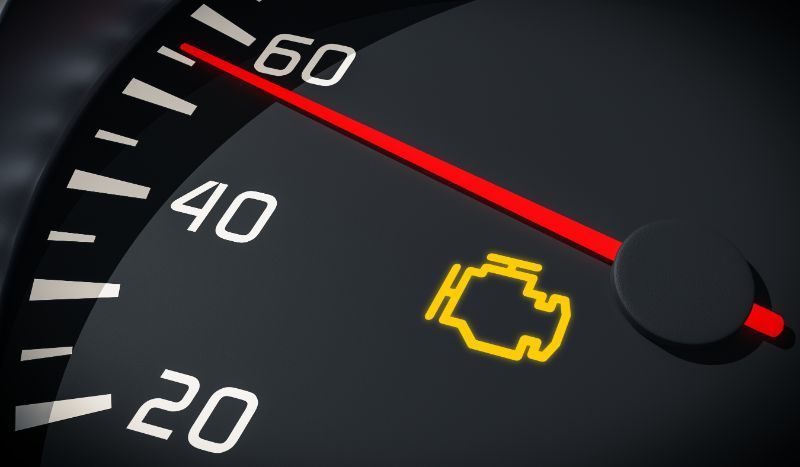 Car dashboard speedometer with red needle and yellow check engine warning light illuminated