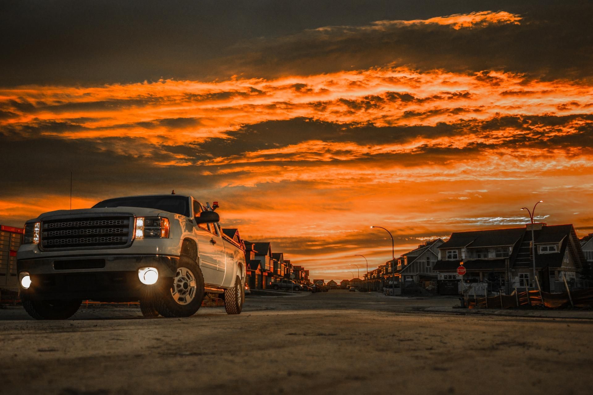 White truck at sunset under a dramatic orange sky in an open lot