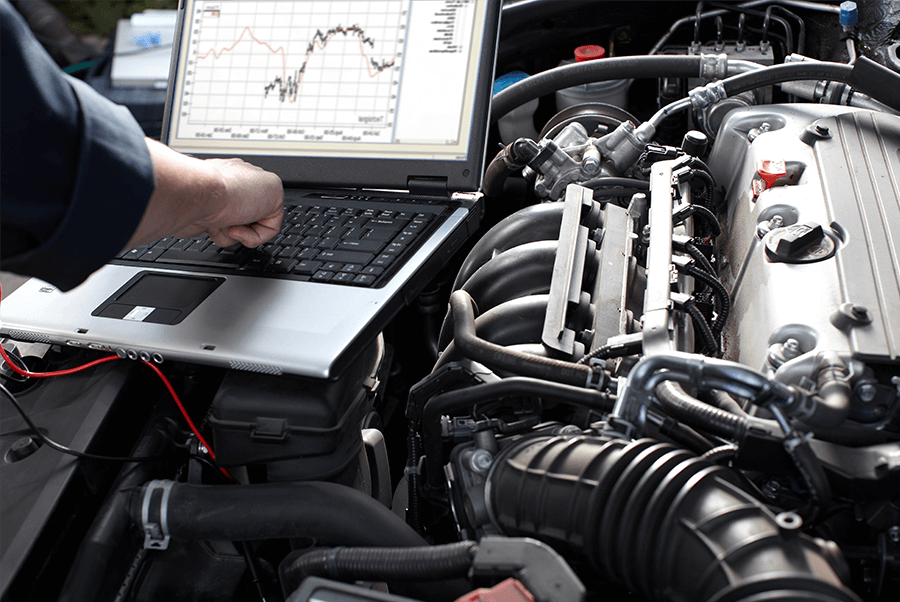 Mechanic diagnosing a car engine with a laptop and live data graph under the hood