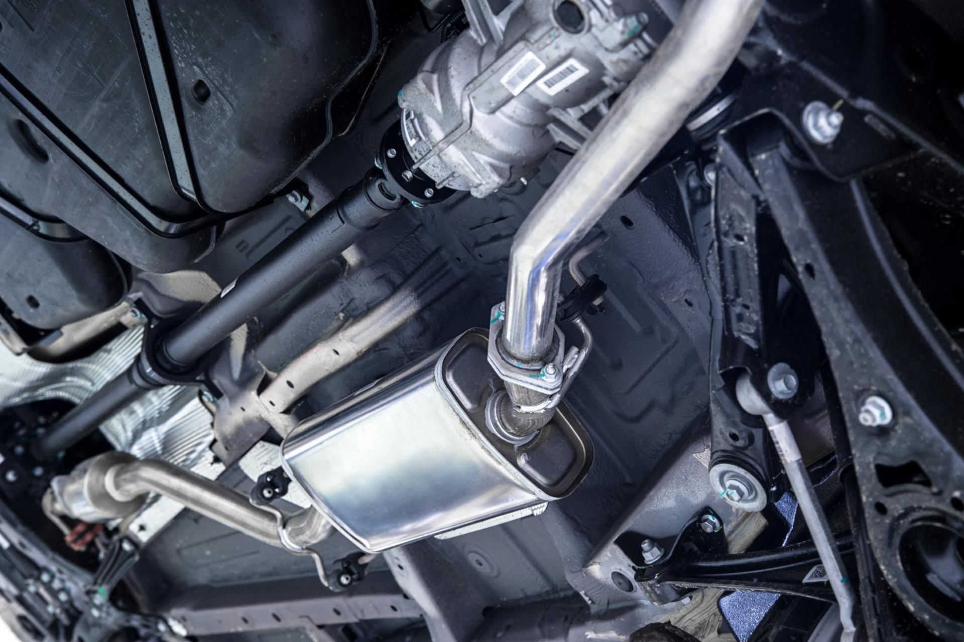 Undercarriage of a car showing exhaust piping and a silver muffler