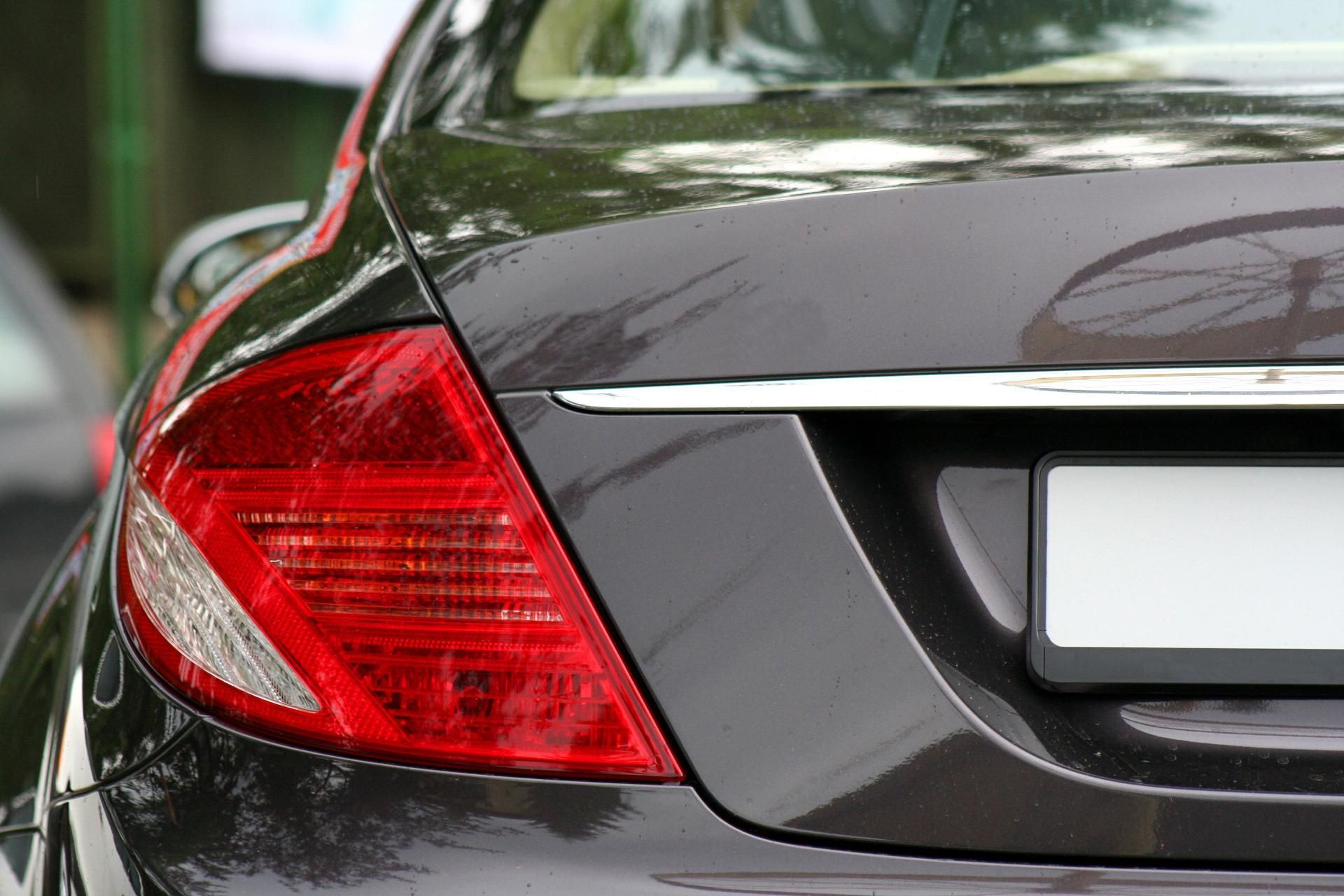 Rear view of a dark gray car showing the left taillight and trunk badge area