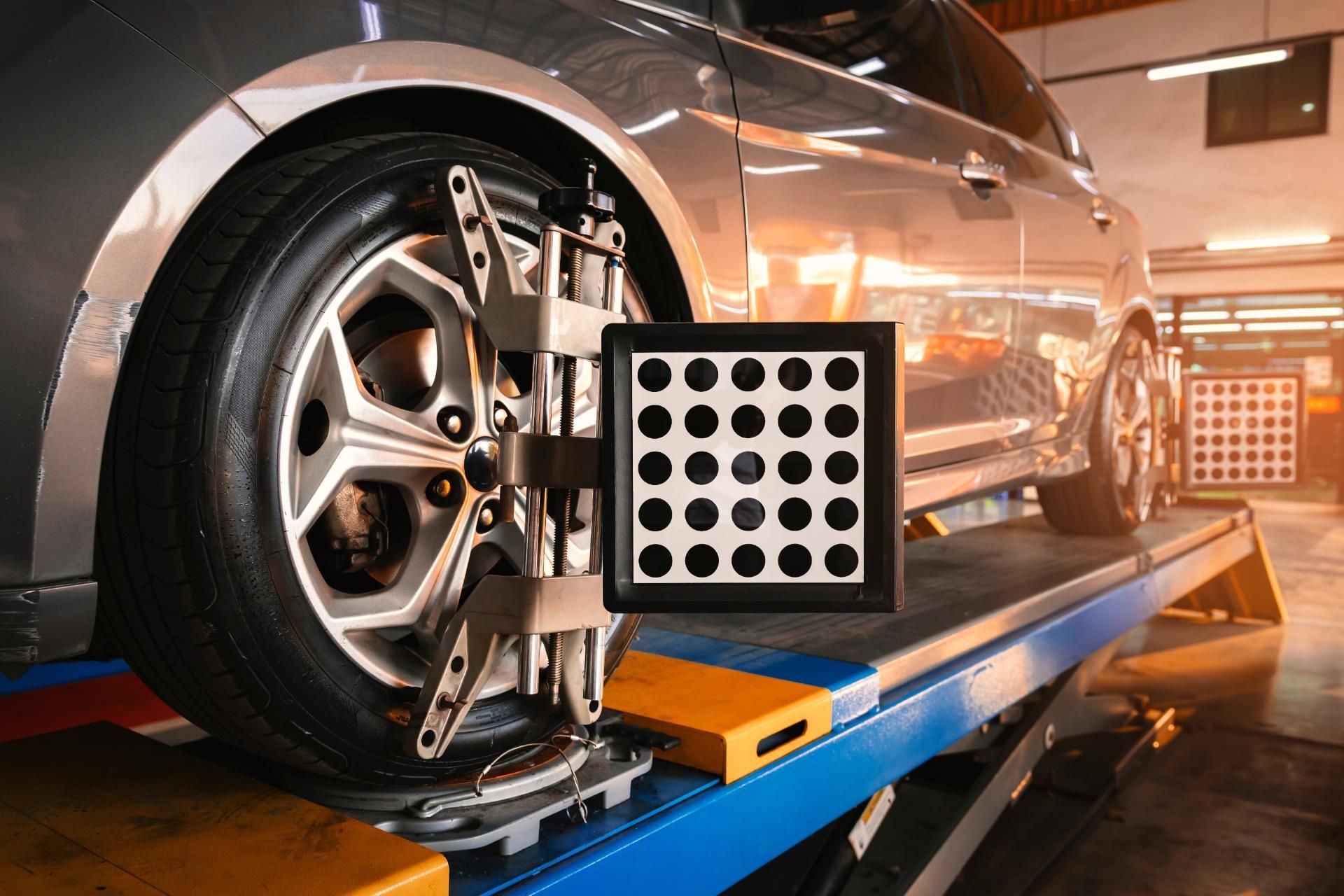 Car on a wheel alignment machine in an auto repair shop, with a measuring target mounted on the wheel.