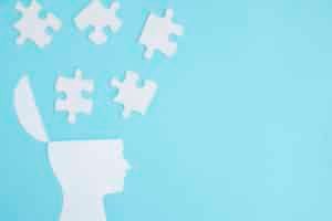 Silhouette head with open top and puzzle pieces floating out, light blue background.
