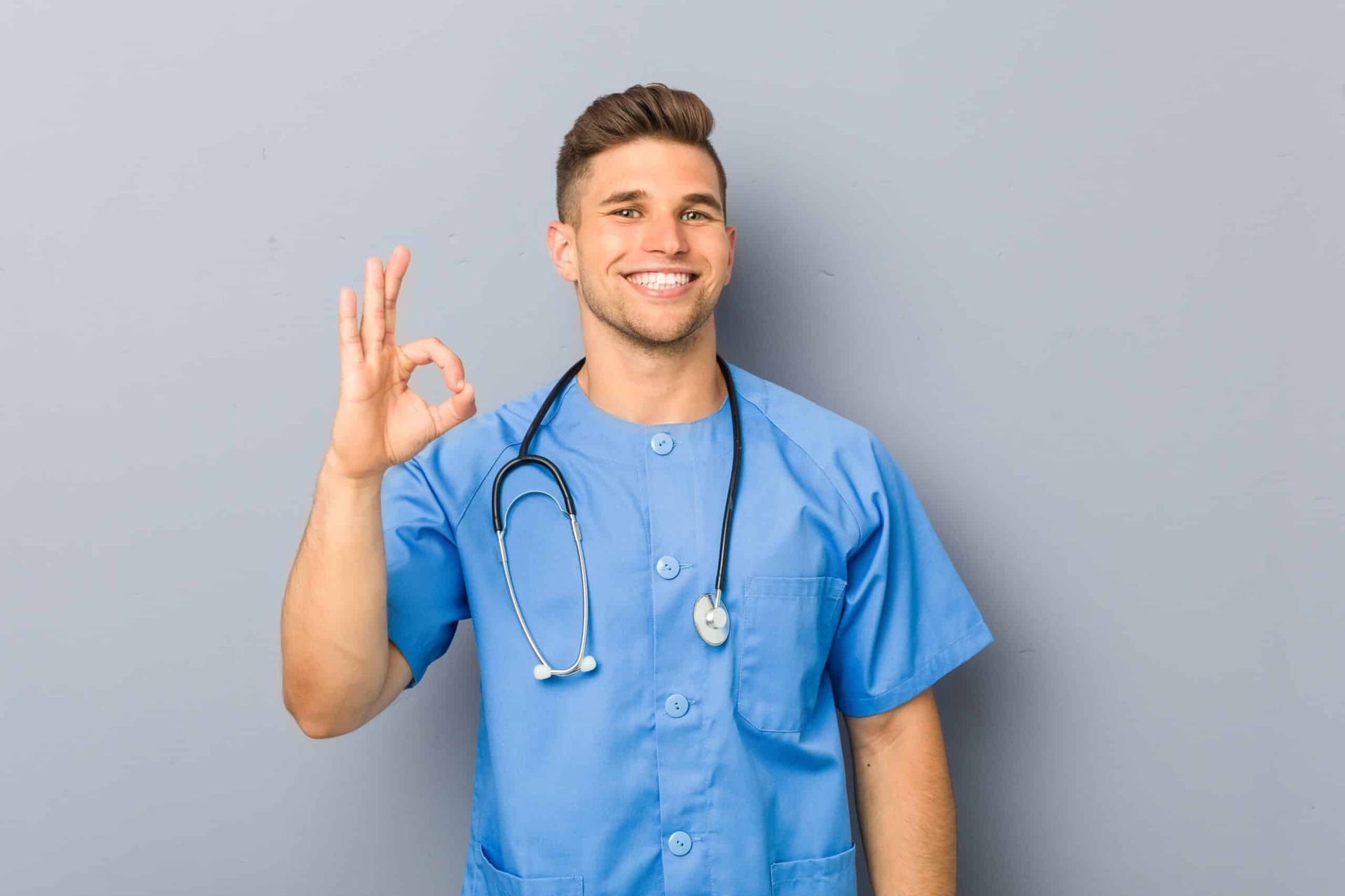 Smiling medical professional in blue scrubs giving the 