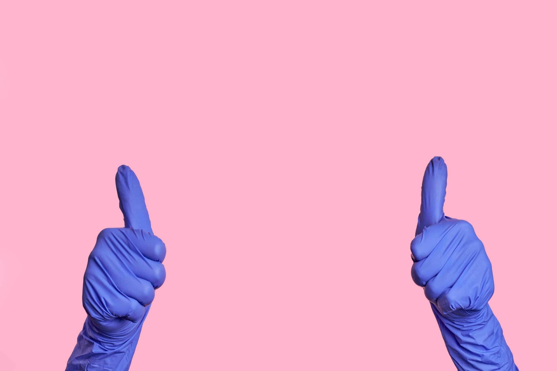 Two hands in blue gloves pointing up on pink background.