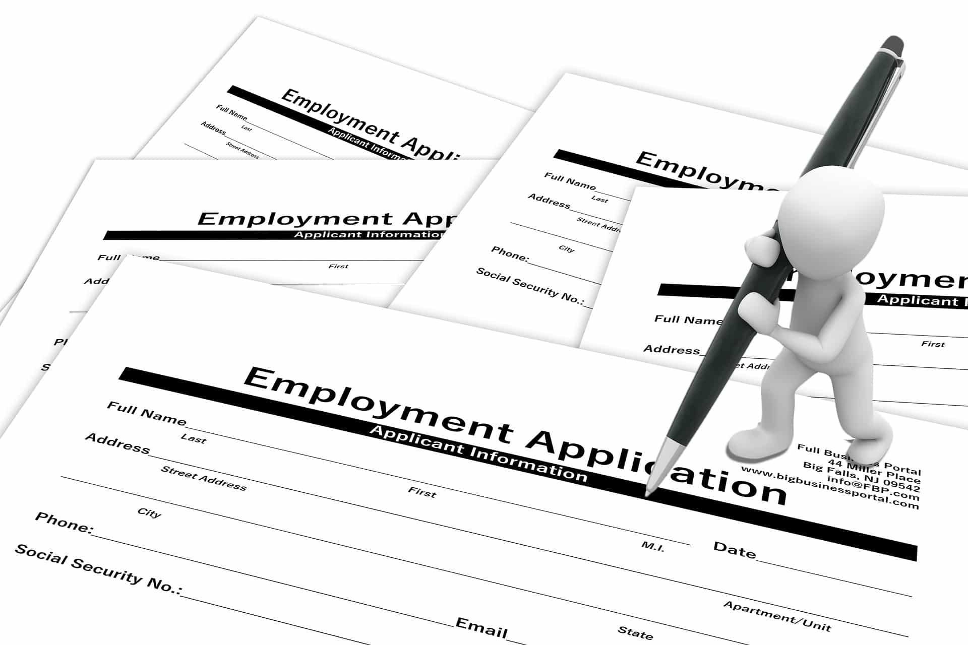 A white stick figure writing on an employment application, surrounded by multiple forms.