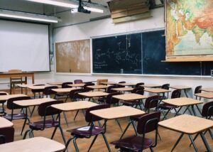 Empty classroom with desks, a chalkboard, and a projector screen.
