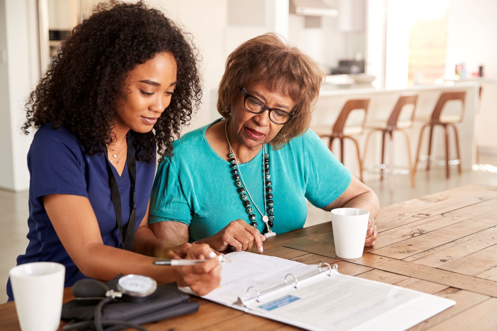 Two women reviewing documents together at a wooden table in a bright office