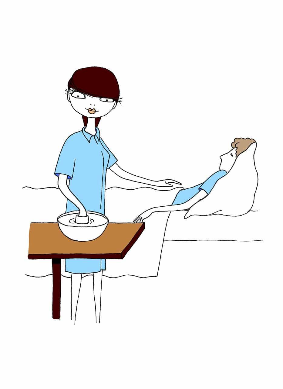 Nurse in blue scrubs tending to a patient in bed. A bowl sits on a nearby table.
