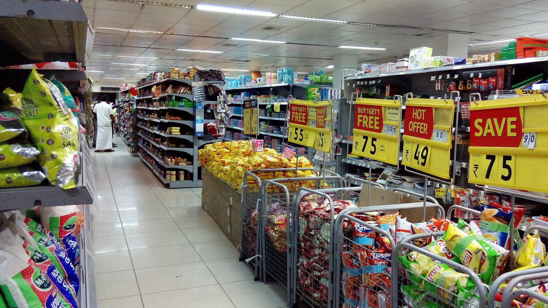Interior of a brightly lit grocery store with shelves of products and sale signs, showcasing various items for purchase.