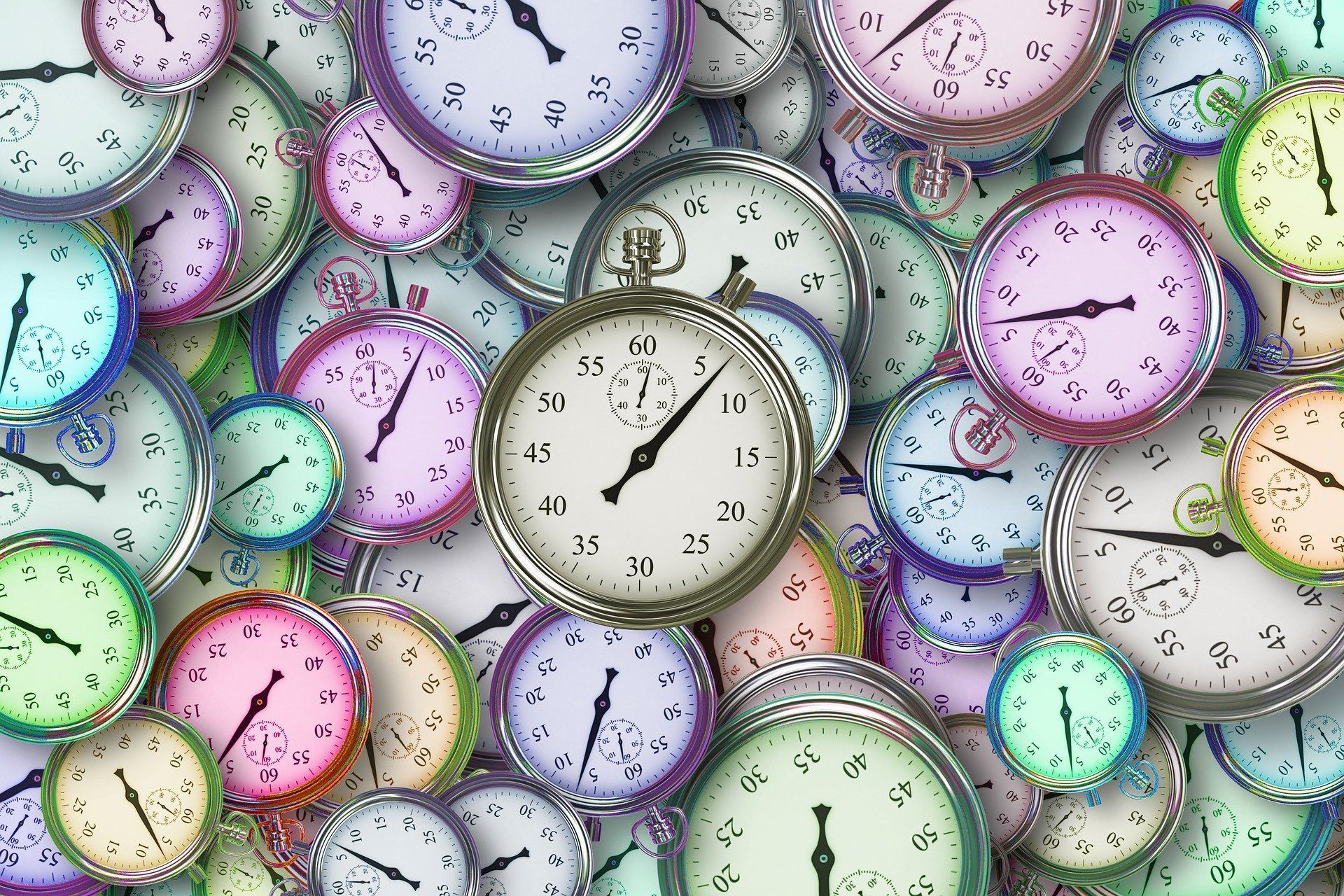 Cluttered arrangement of clocks, mostly round with colorful faces and hands pointing at various times.