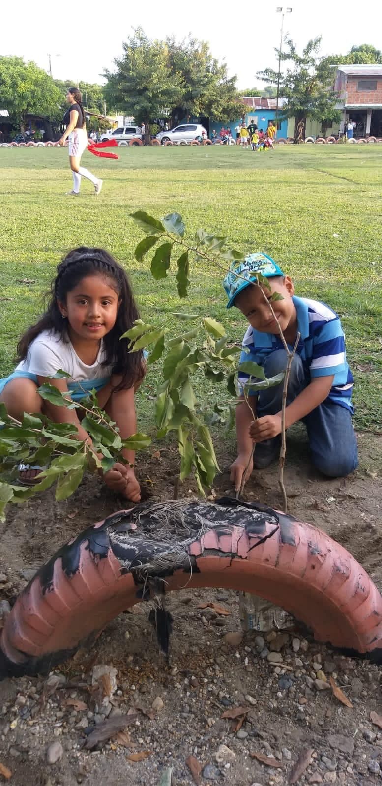 Un niño y una niña están plantando un árbol en un neumático.