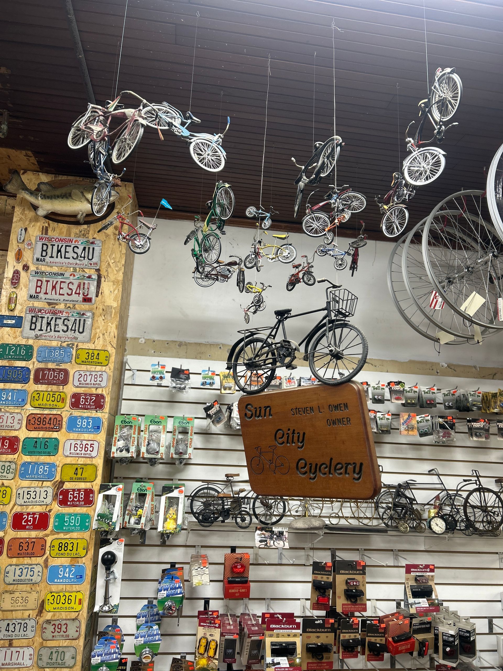 Bicycle shop display with hanging bike decor, shelves of accessories, and rows of toy cars and bicycles