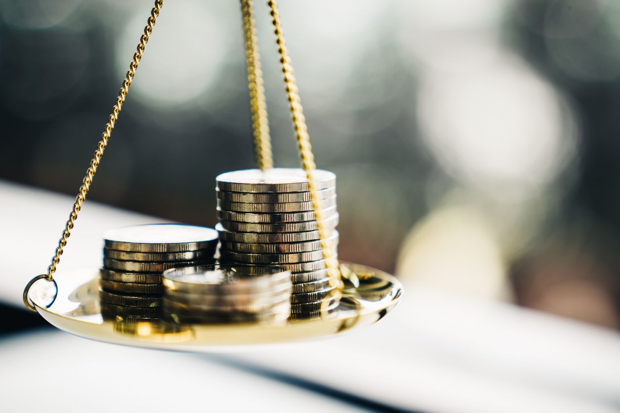 Golden balance scale with stacks of coins on one side.
