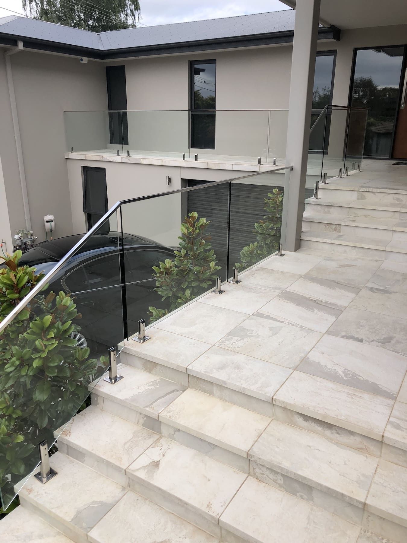 A set of stairs leading up to a house with a glass railing.