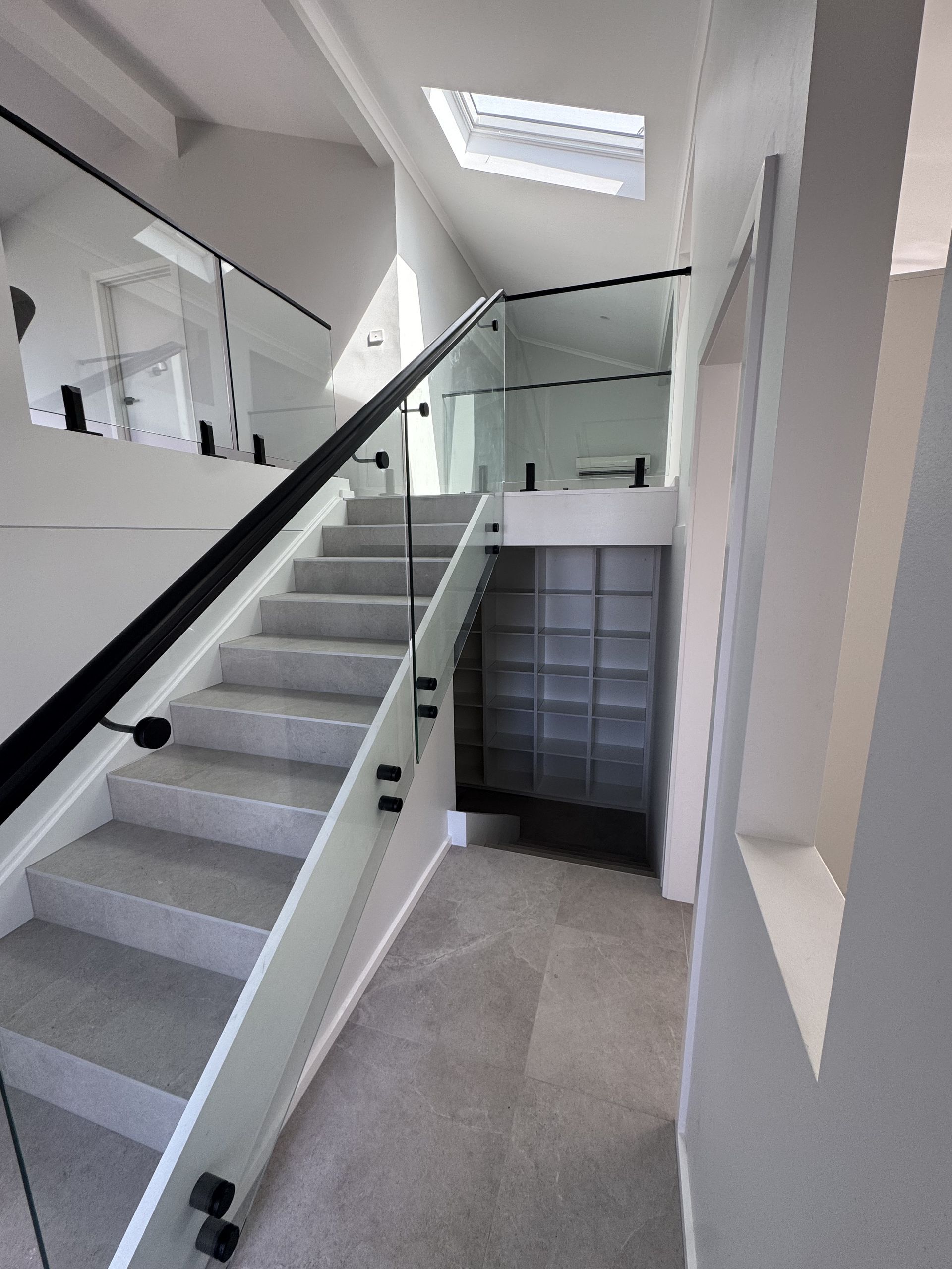 A staircase with a glass railing and a skylight in the background.
