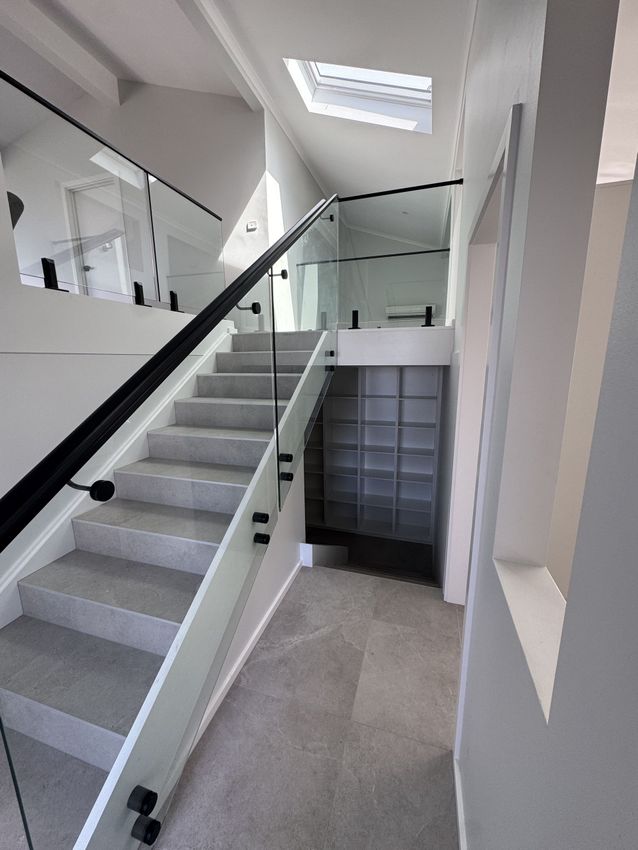 A staircase with a glass railing and a skylight in the background.