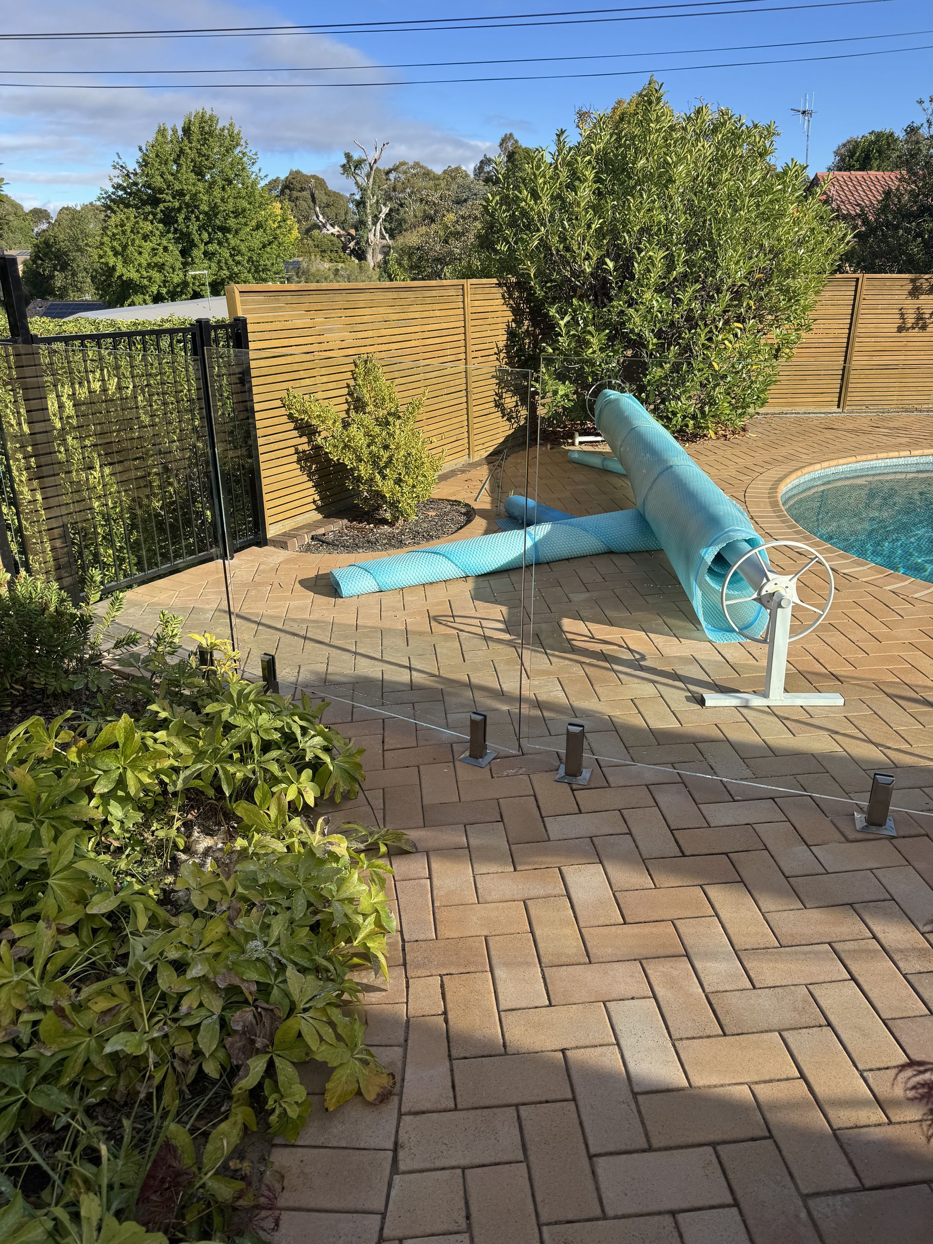 A swimming pool is surrounded by a brick patio and a fence.