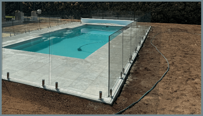 Frameless glass pool fencing around a backyard swimming pool in Canberra with stainless steel spigots.
