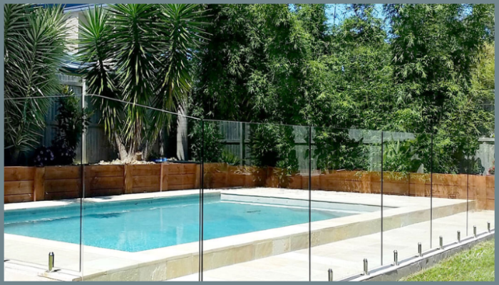 Frameless glass pool fence with stainless steel spigots and lush garden backdrop