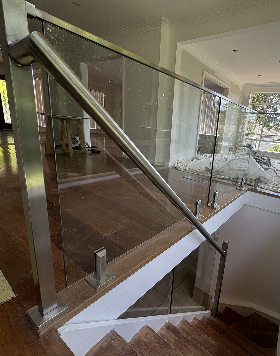 A staircase with a glass railing and a stainless steel railing.