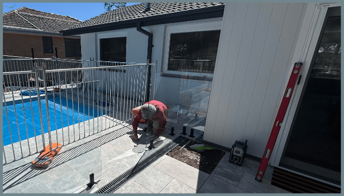 Installer securing frameless glass pool fencing beside a residential swimming pool in Canberra to ensure safety and long-term performance.