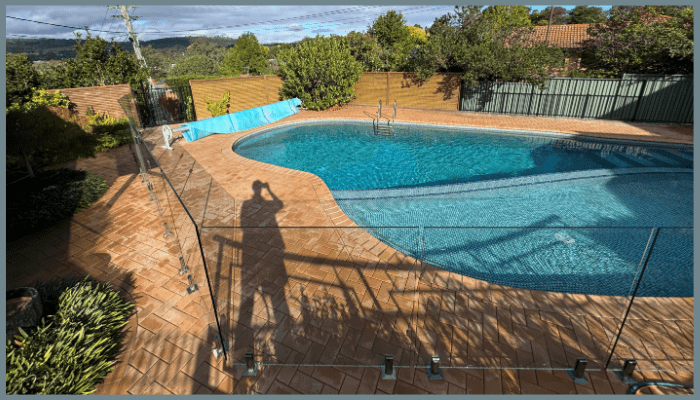 Pool with blue water and person's shadow taking a picture on a sunny day.