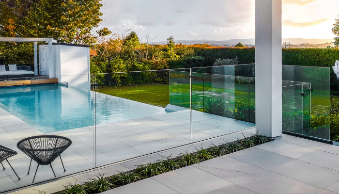Luxury backyard with frameless glass pool fencing, illustrating the high cost of premium pool fence installations.