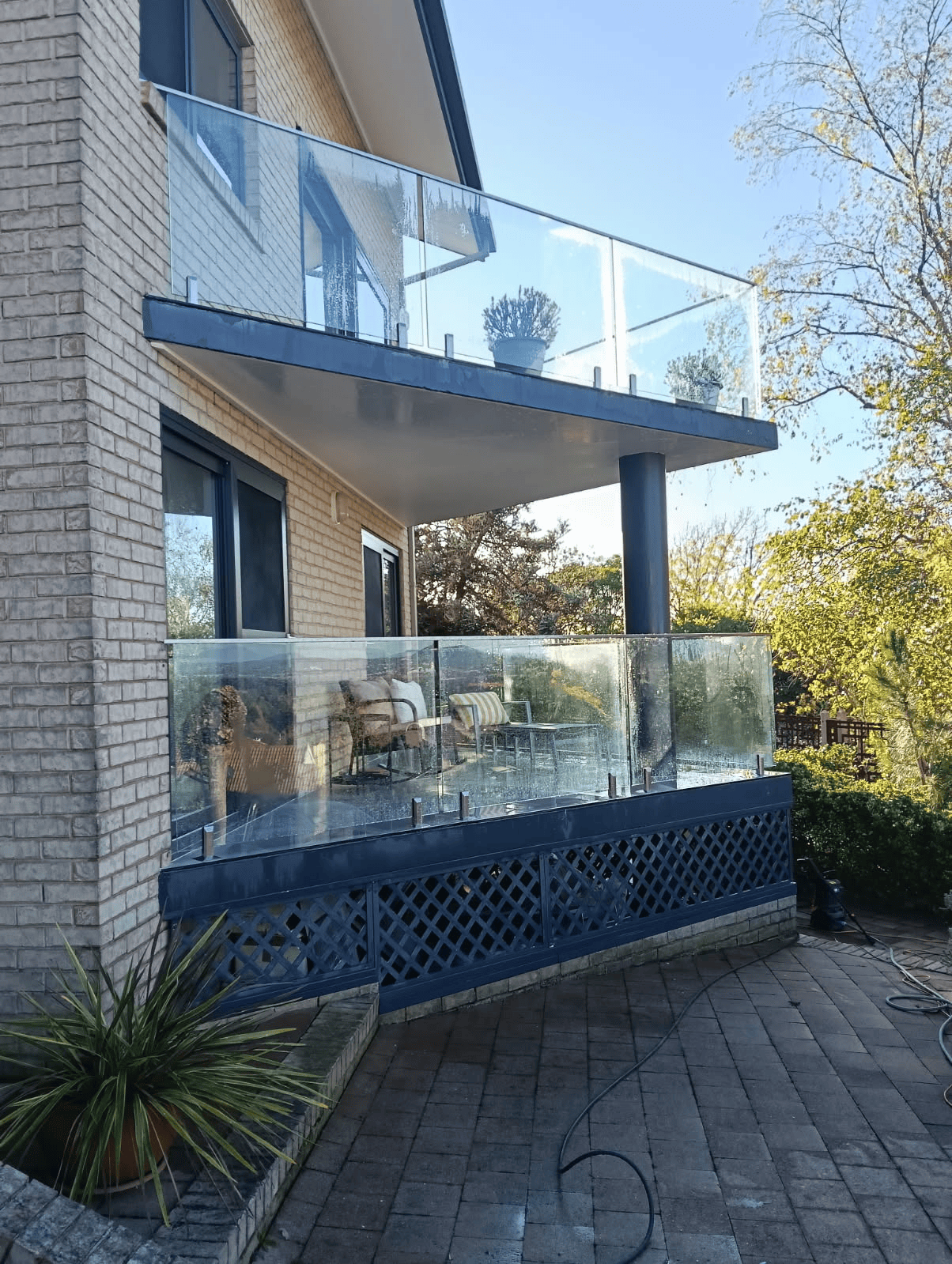 A balcony with a glass railing on the side of a house.
